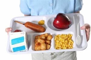 A student holding a tray of school lunch.