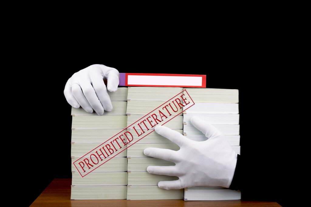 Two hands over stacks of books with “prohibited literature” text