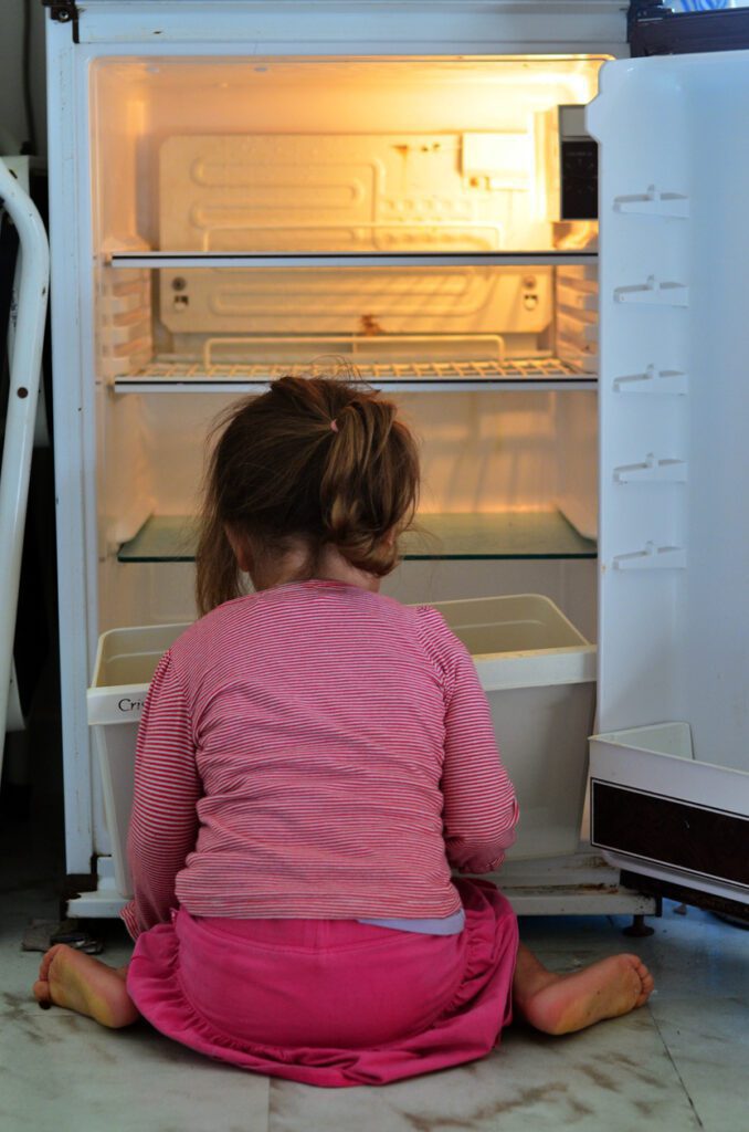 A girl sitting on the floor while looking at a crisper